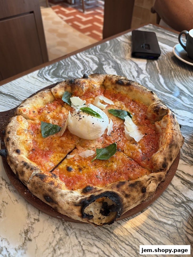 A delicious pizza with fresh basil and burrata cheese on a marble table.