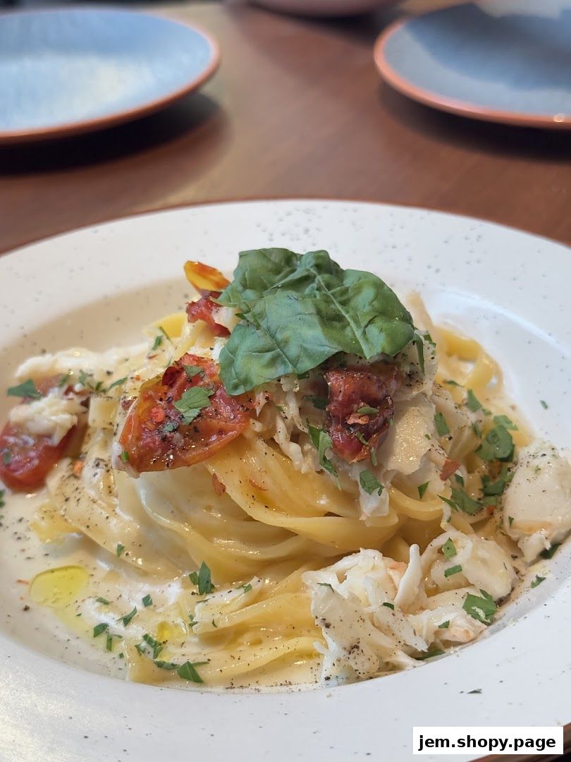 A close-up of a creamy pasta dish with crab meat, sun-dried tomatoes, and fresh herbs.