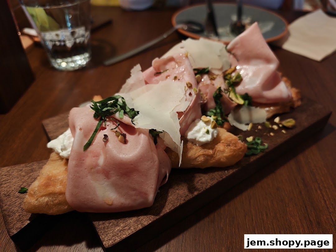A wooden board with mortadella, cheese, and fried dough, garnished with herbs and pistachios.