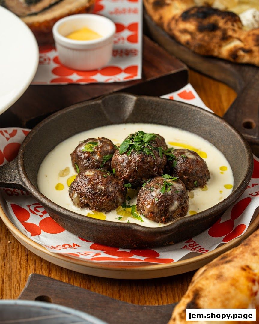 A cast iron skillet filled with meatballs in a creamy sauce, garnished with parsley.