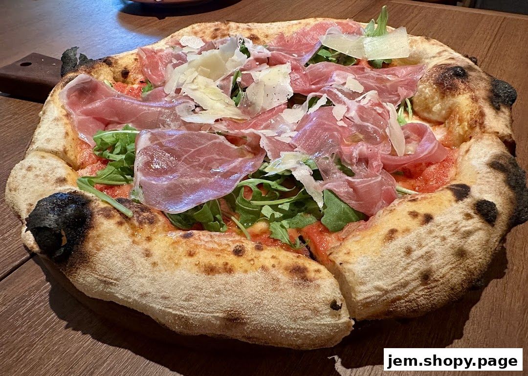 A close-up shot of a delicious pizza topped with prosciutto, arugula, and shaved parmesan cheese.