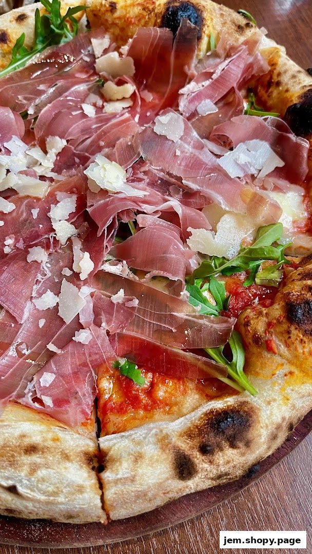 A close-up shot of a delicious pizza topped with prosciutto and shaved parmesan cheese.