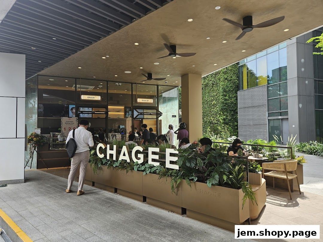 The exterior of a CHAGEE shop with outdoor seating and lush greenery.
