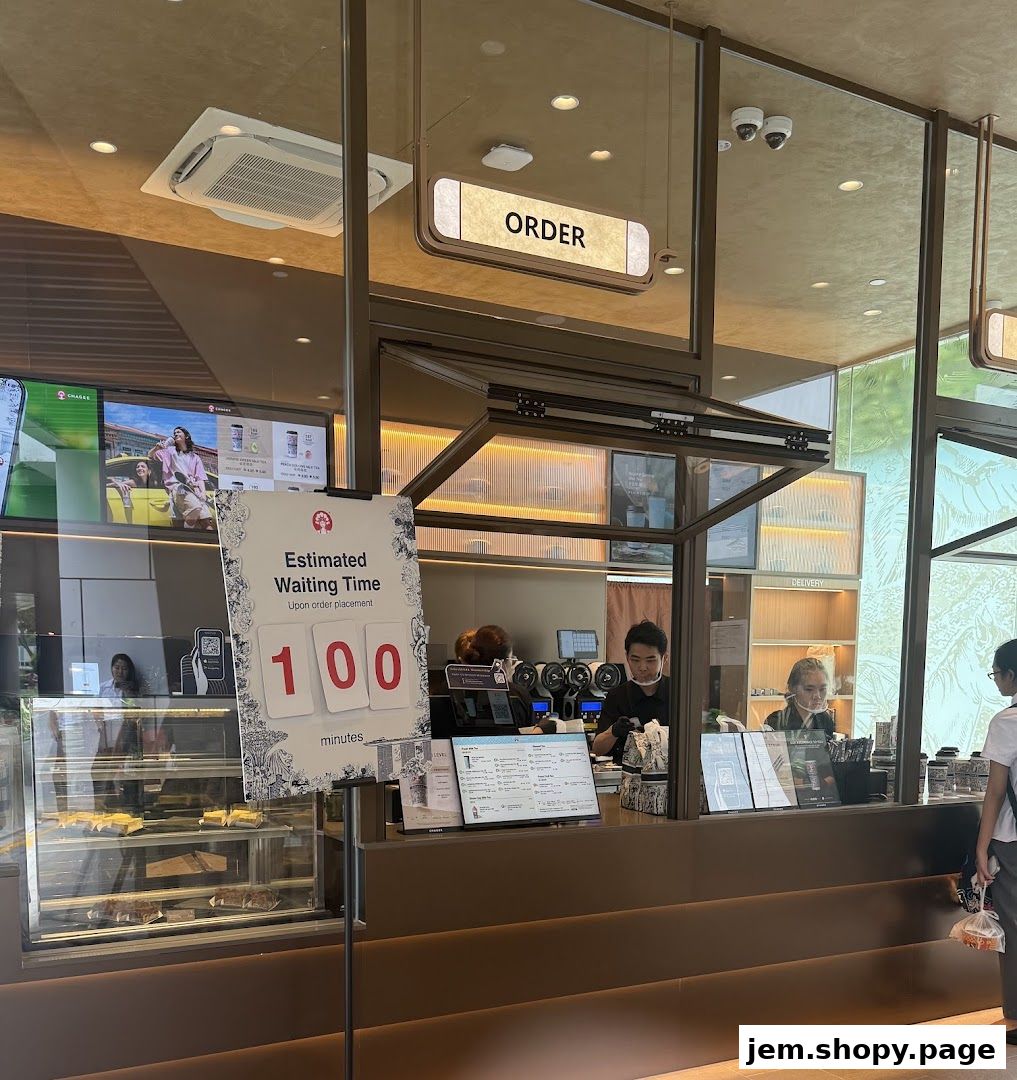A CHAGEE shop counter with an estimated waiting time sign and staff serving customers.