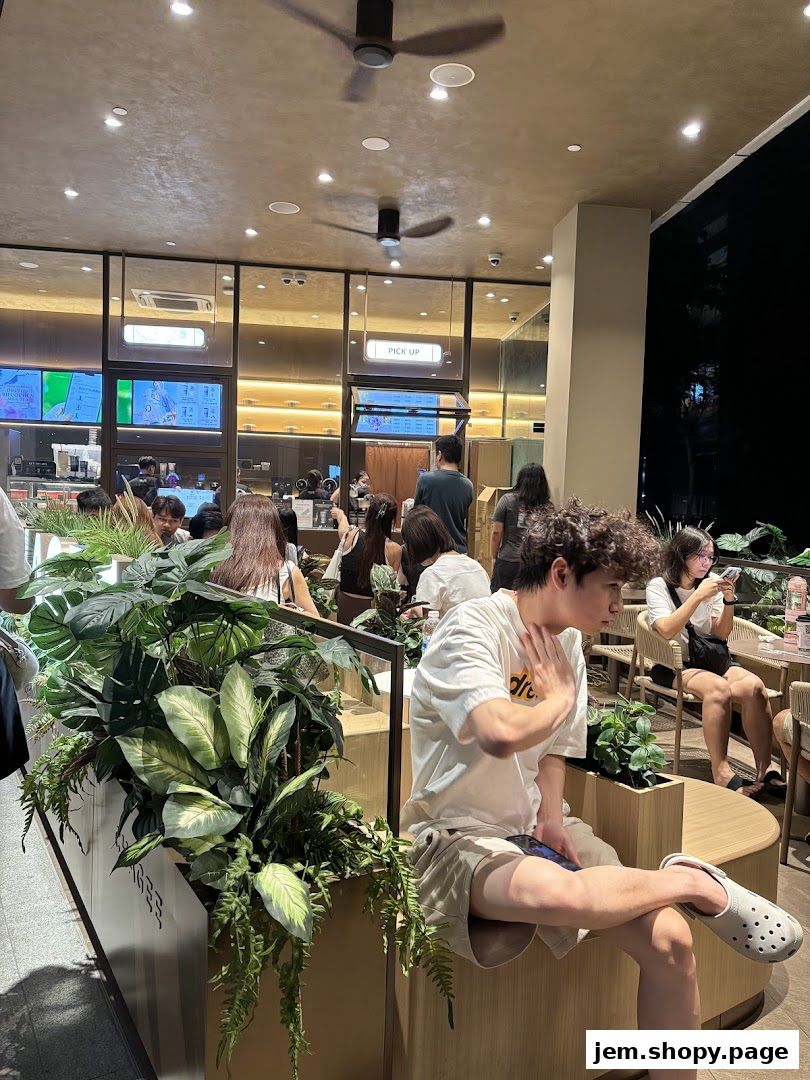 People are seated and waiting at CHAGEE JEM, a modern tea shop with lush greenery.