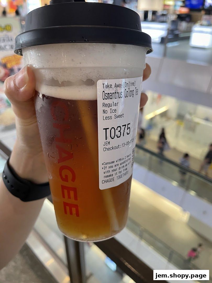 A hand holds a CHAGEE Osmanthus Oolong Tea with no ice and less sweet.