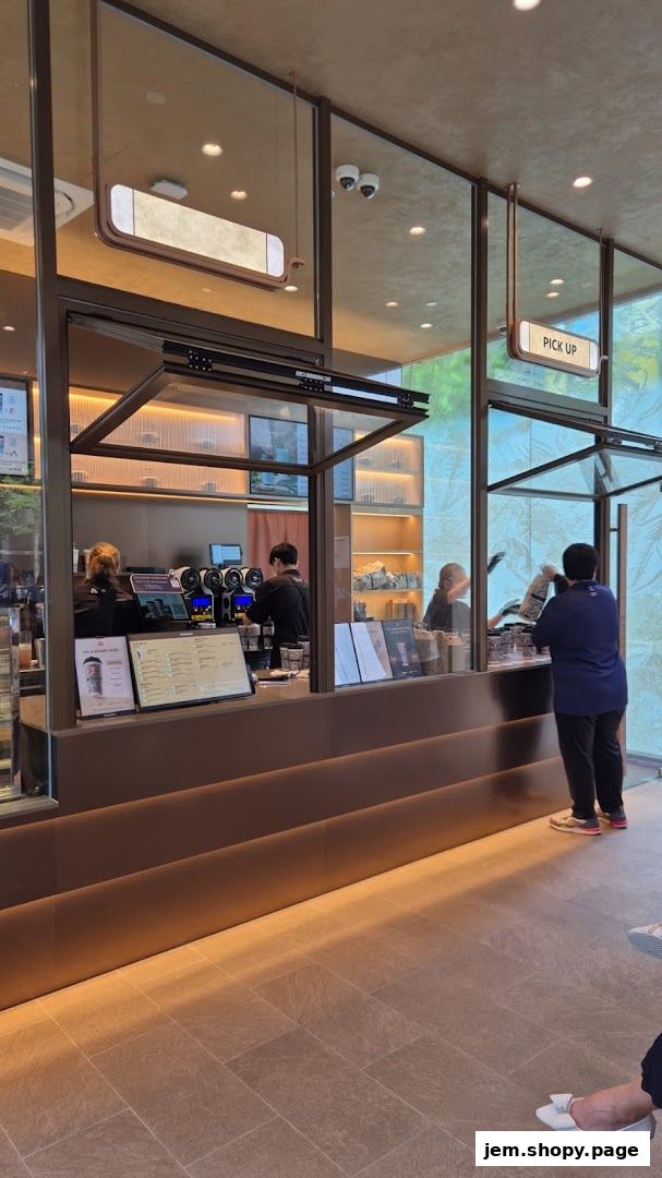 Customers ordering and picking up drinks at a modern CHAGEE tea shop counter.