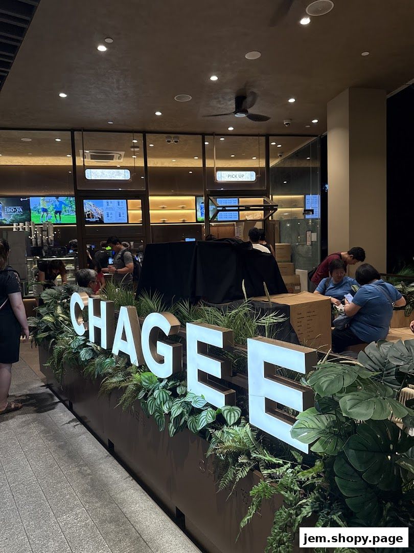The CHAGEE shop front with illuminated signage and lush greenery.
