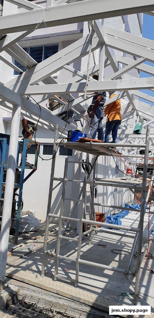 Workers on scaffolding are constructing a white metal roof structure.