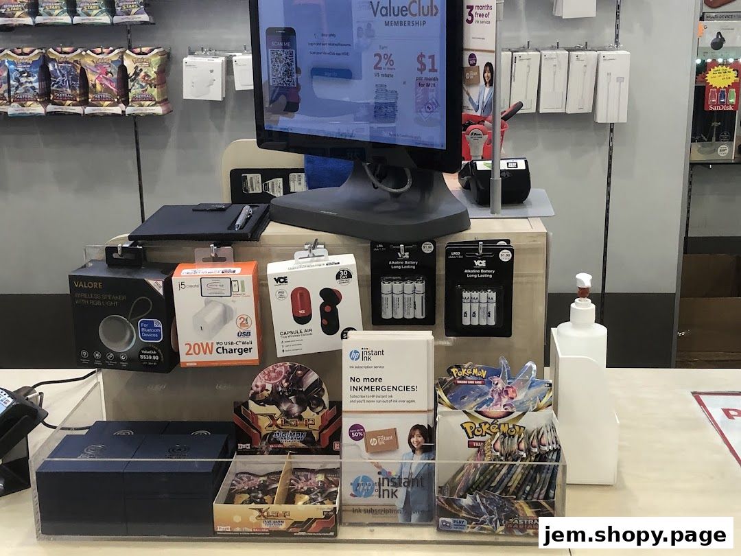Counter display at Challenger JEM featuring electronics, charging accessories, and trading card packs.