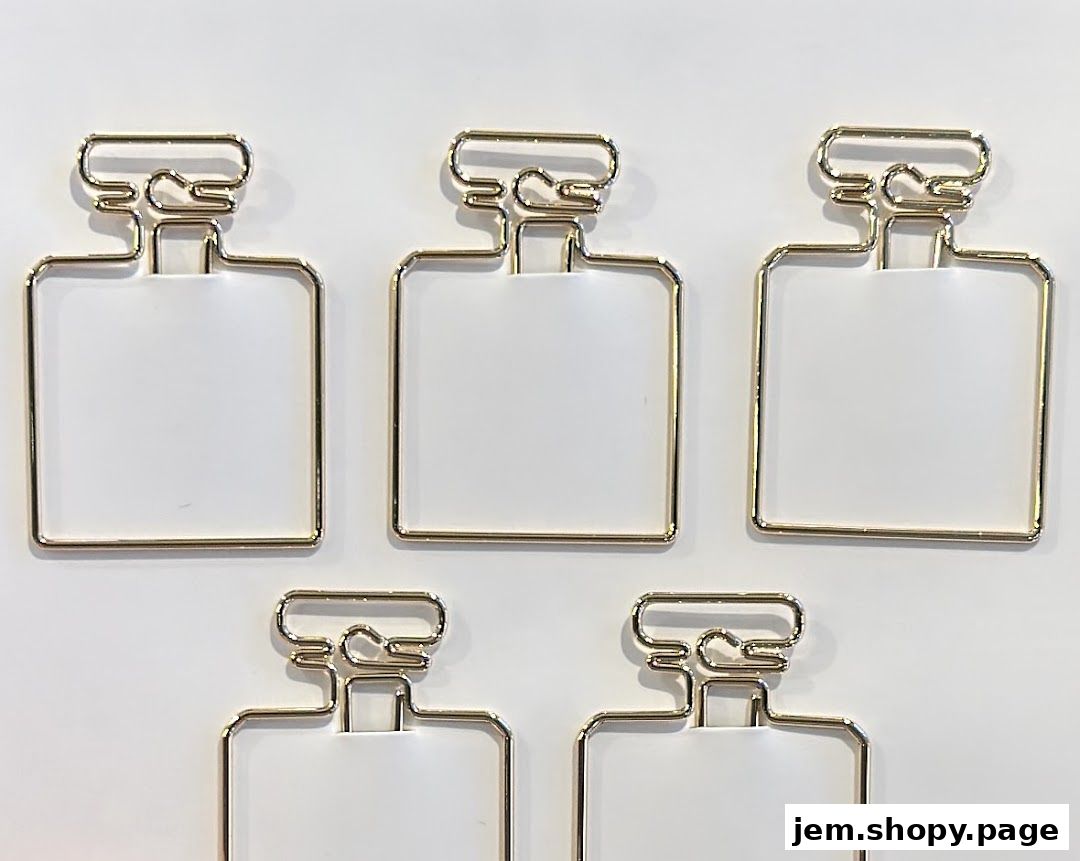 Five gold perfume bottle shaped paper clips on a white background.