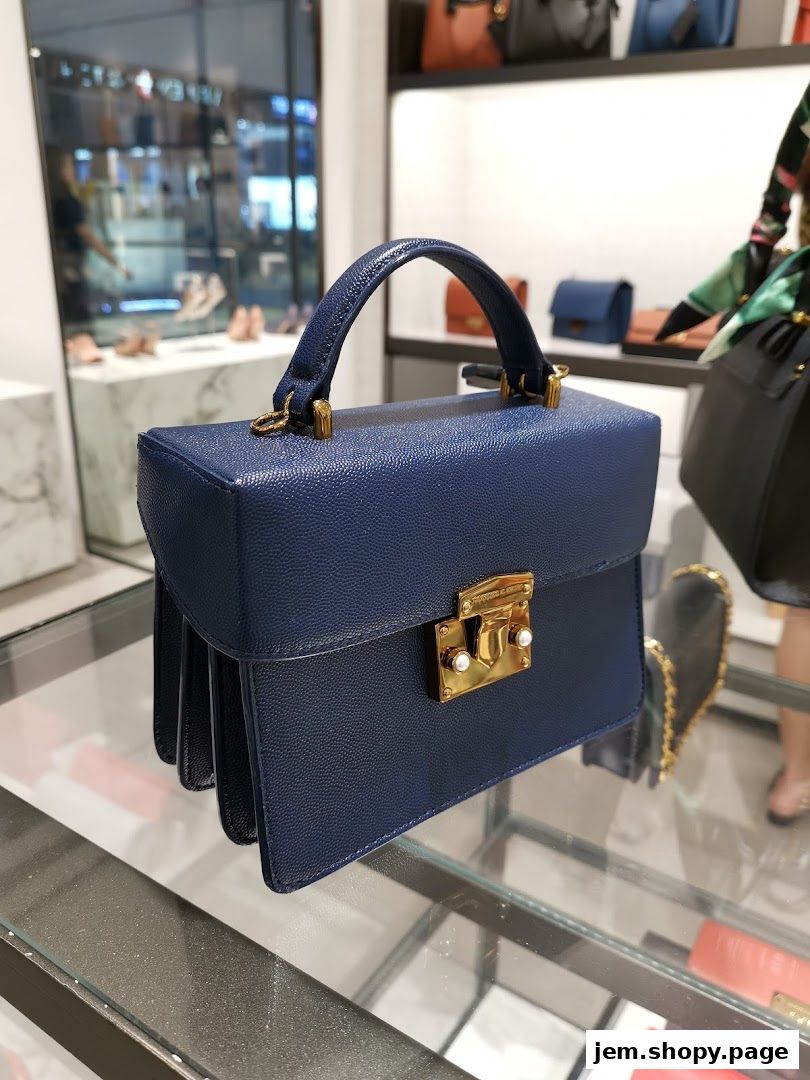 A close-up of a navy blue Charles & Keith handbag with gold hardware on display.