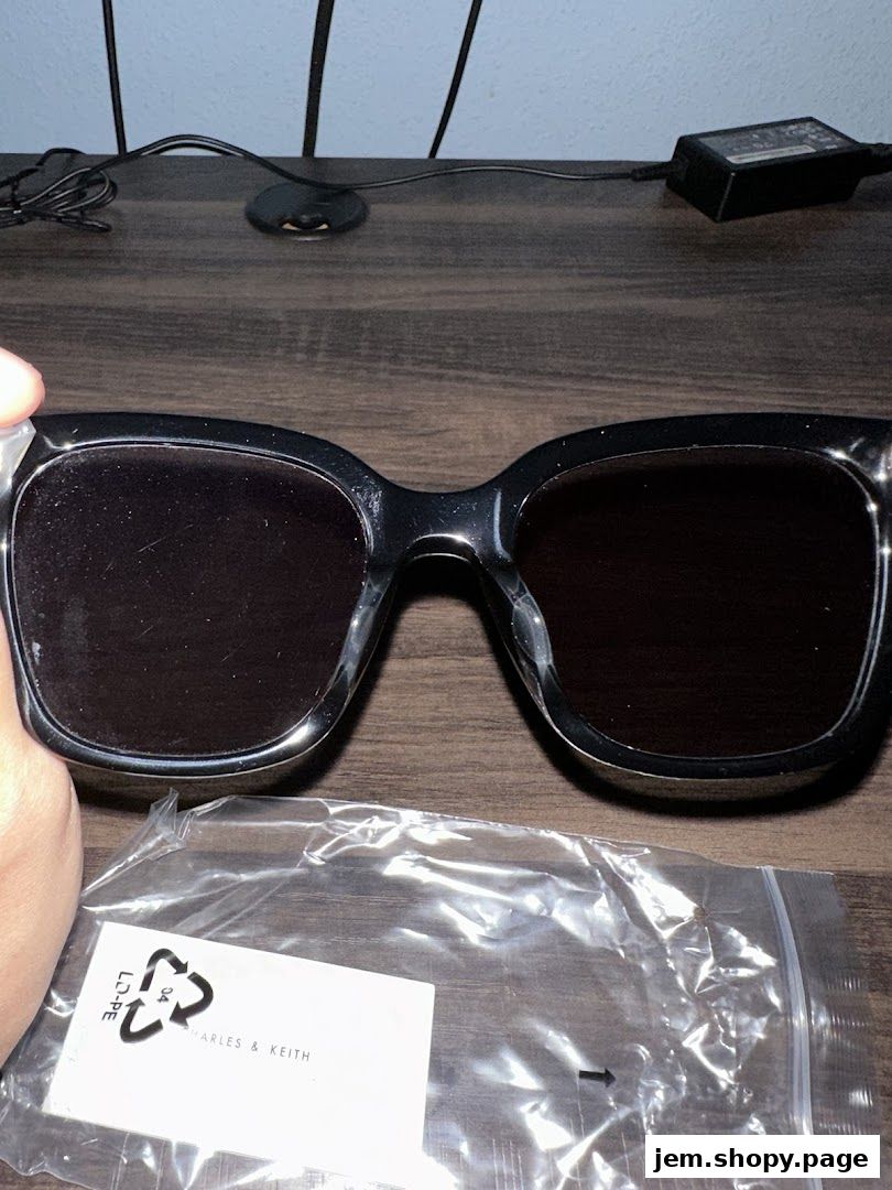 A pair of black Charles & Keith sunglasses with a plastic bag.