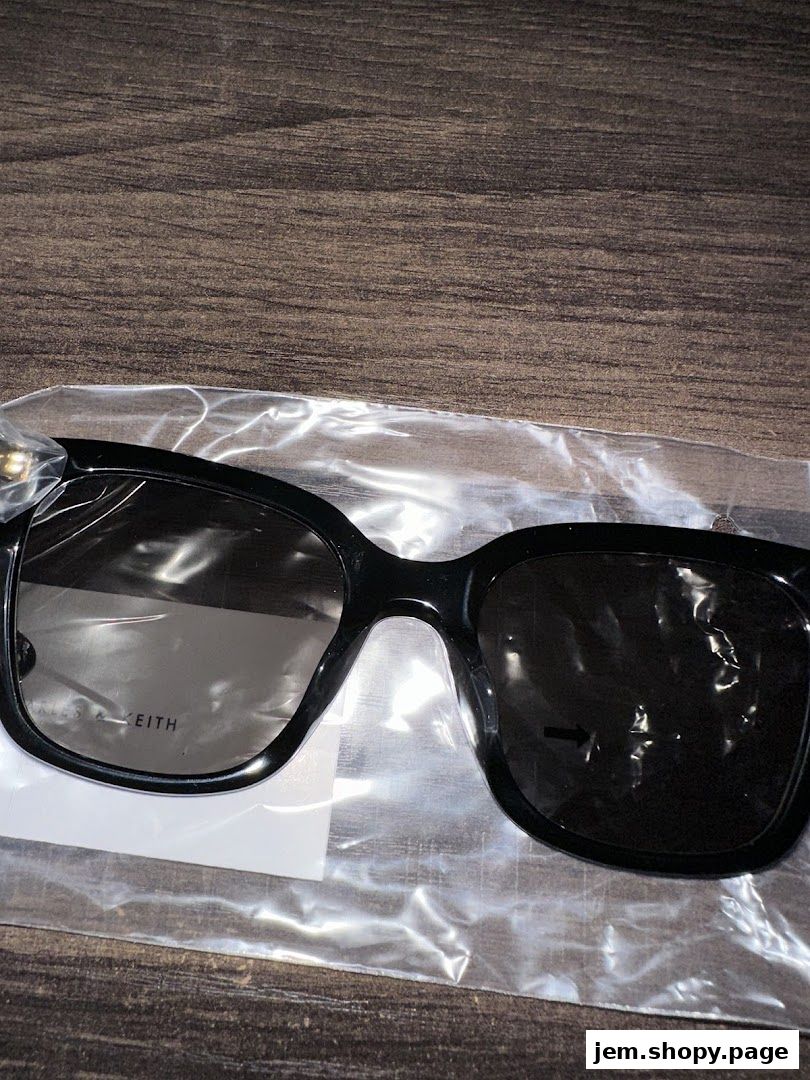 A pair of black Charles & Keith sunglasses in plastic packaging on a wooden surface.