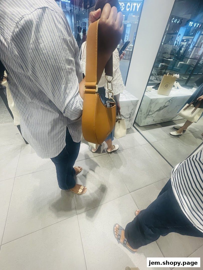 A person holds a stylish brown handbag inside a CHARLES & KEITH store.
