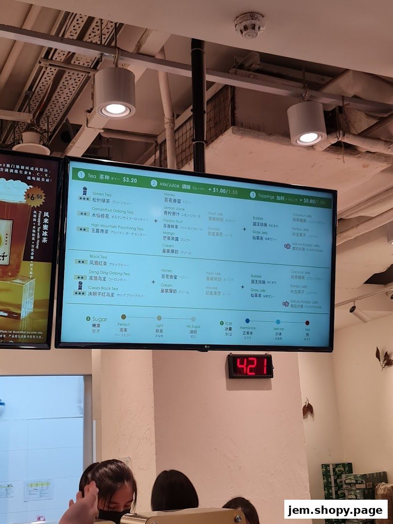 A digital menu board displays various tea and juice options with prices and customization choices.