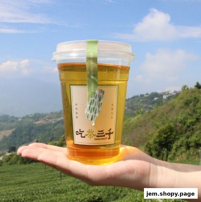 A hand holds a refreshing cup of tea from CHICHA San Chen with a scenic mountain backdrop.