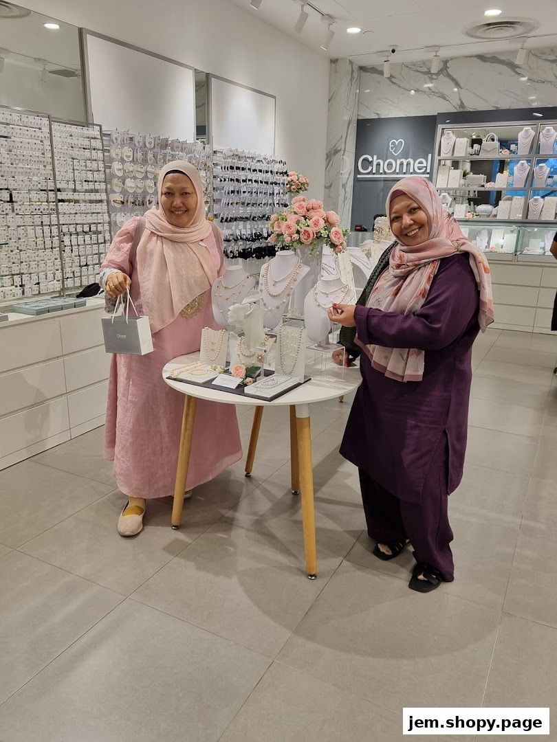 Two women smiling in a jewelry store, showcasing necklaces and accessories.