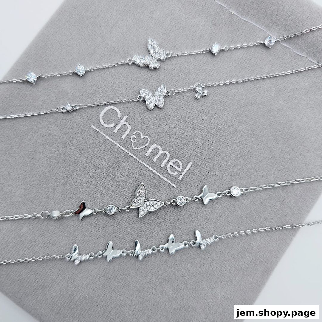 Delicate silver bracelets with butterfly and crystal charms displayed on a grey cloth.
