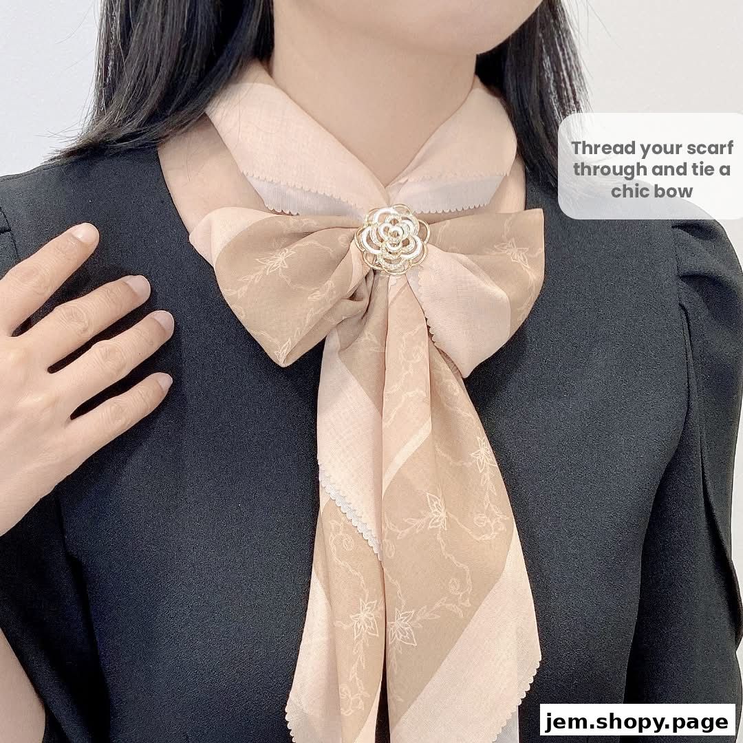 A woman models a chic scarf tied into a bow with a floral brooch.