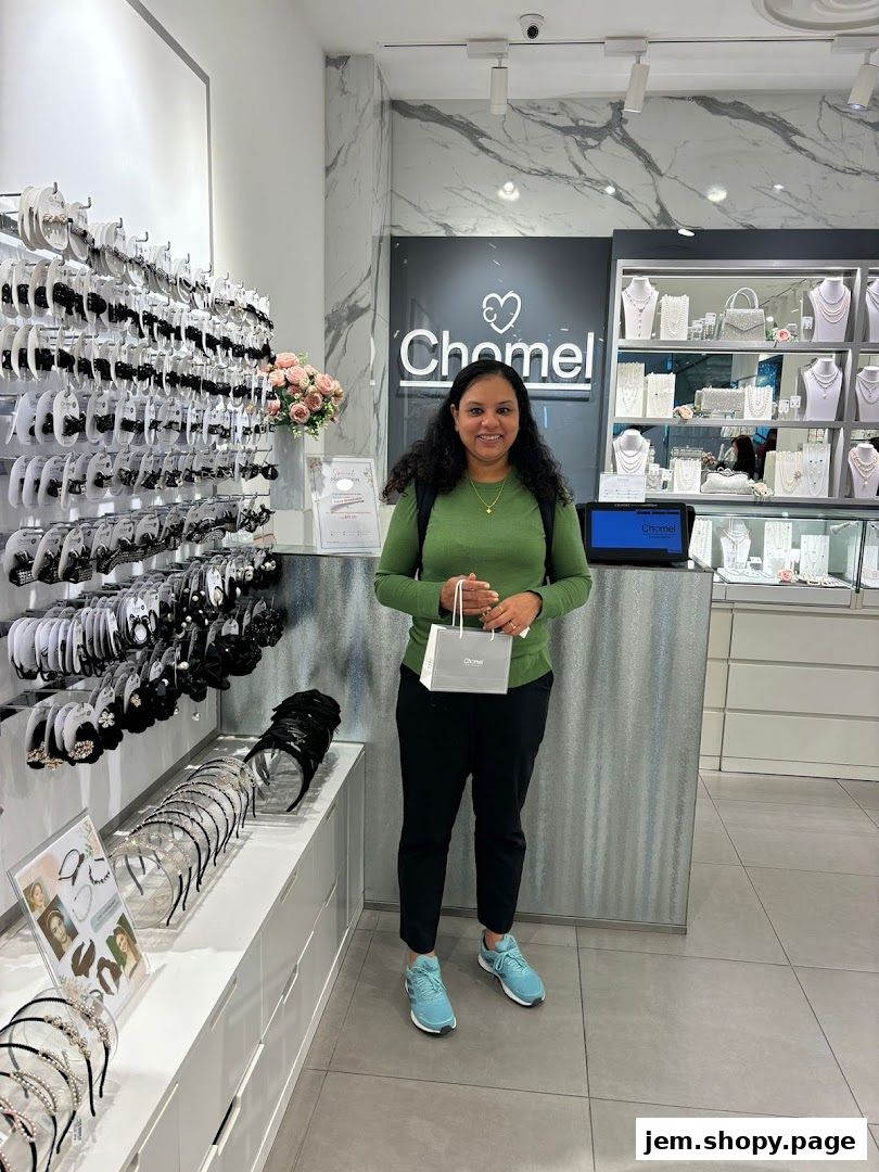 A woman stands in a jewelry store holding a shopping bag from Chomel.