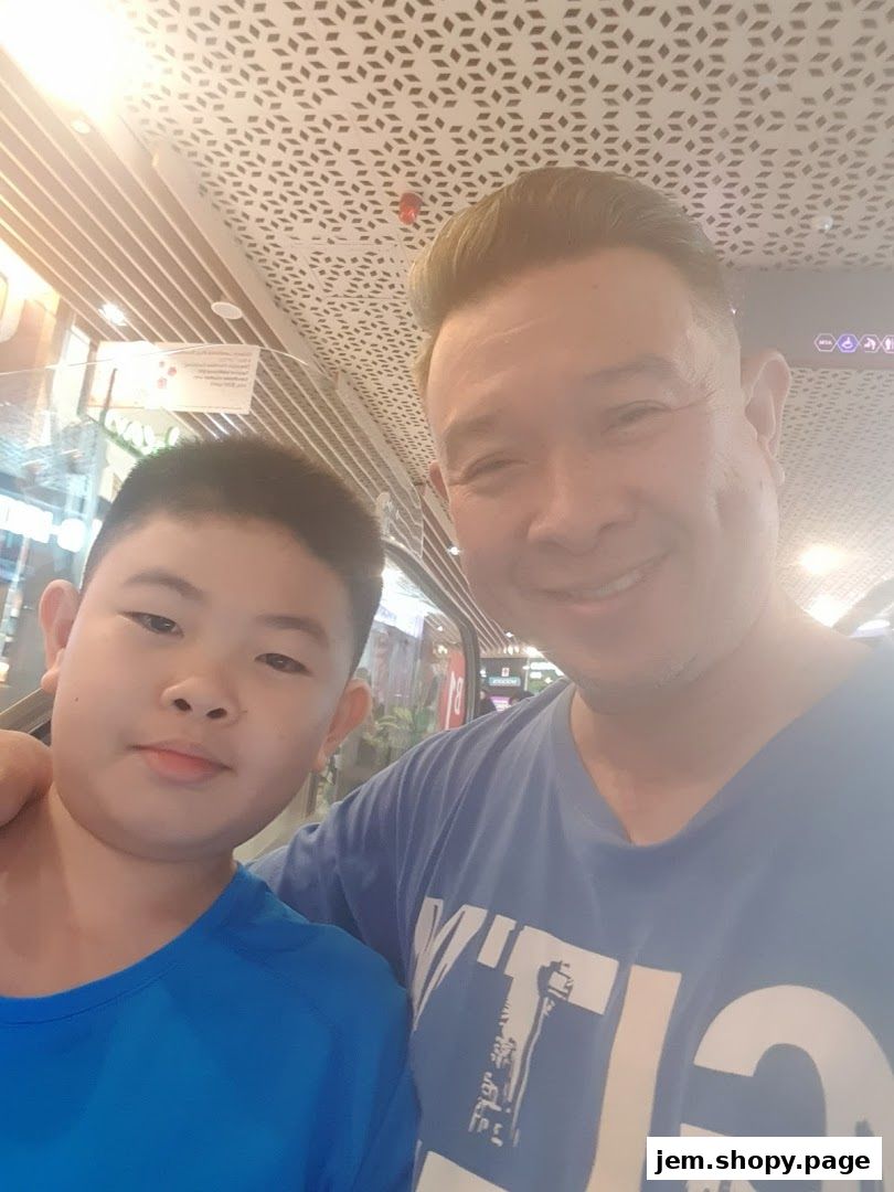 A man and a boy smile for a selfie in a brightly lit indoor space.