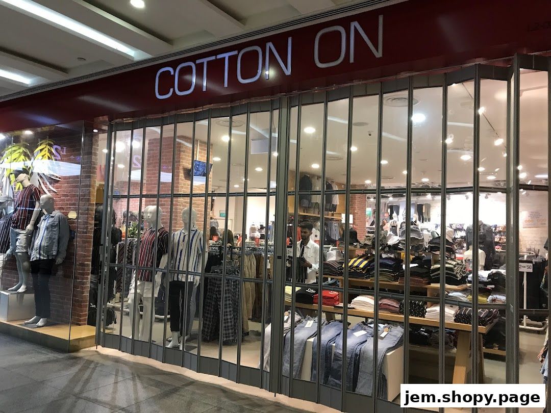 The Cotton On store entrance displays mannequins and folded clothing behind a metal gate.
