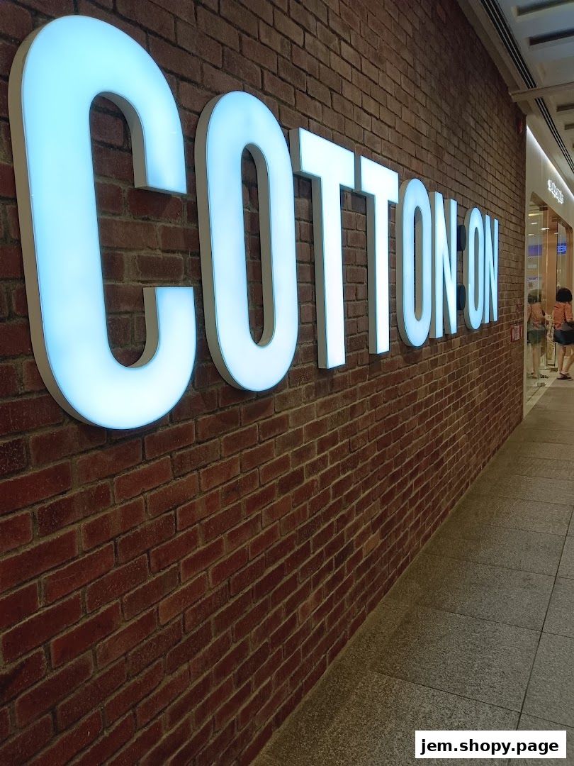 Illuminated Cotton On sign on a brick wall with a glimpse of the store entrance.