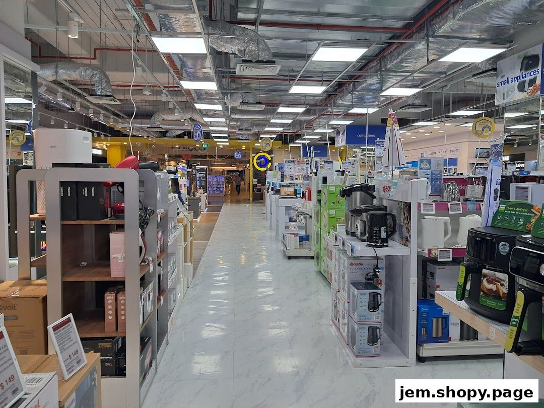 Interior view of a large electronics and home appliance store with aisles of products.