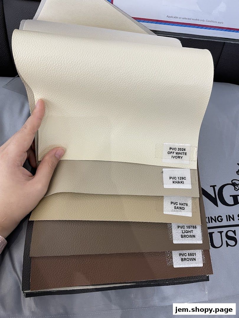 A hand holds swatches of textured material in various neutral shades.