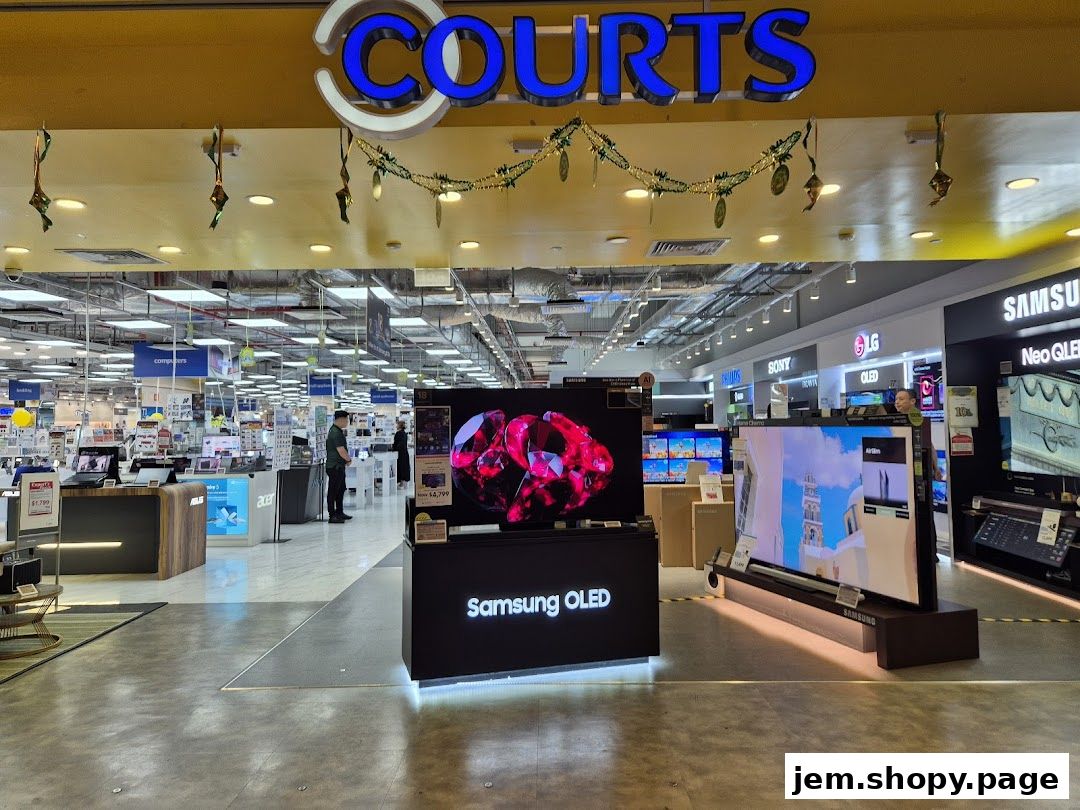 The entrance of COURTS JEM electronics store, showcasing various TVs and computers.