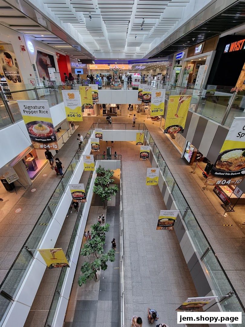 A view of a shopping mall interior with various shops and banners advertising food.