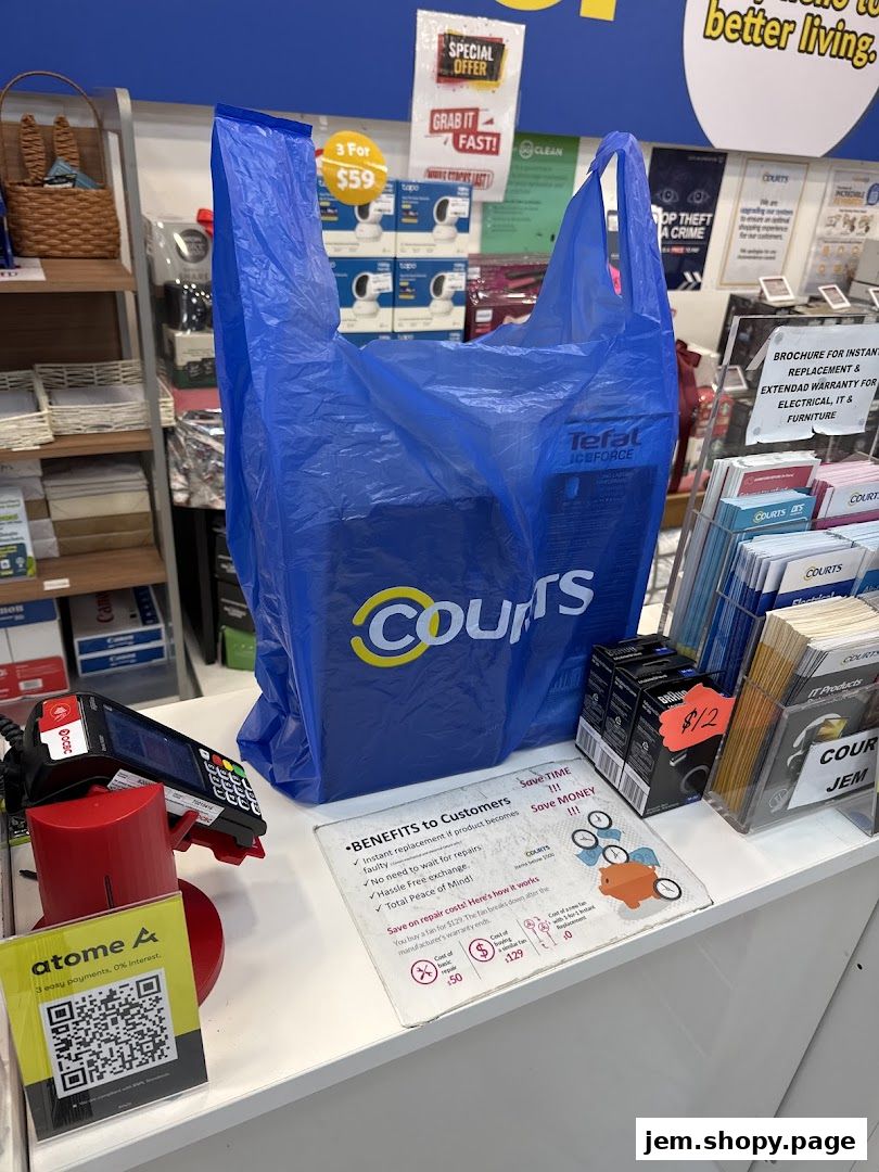 A blue COURTS shopping bag sits on a counter with promotional materials and a payment terminal.