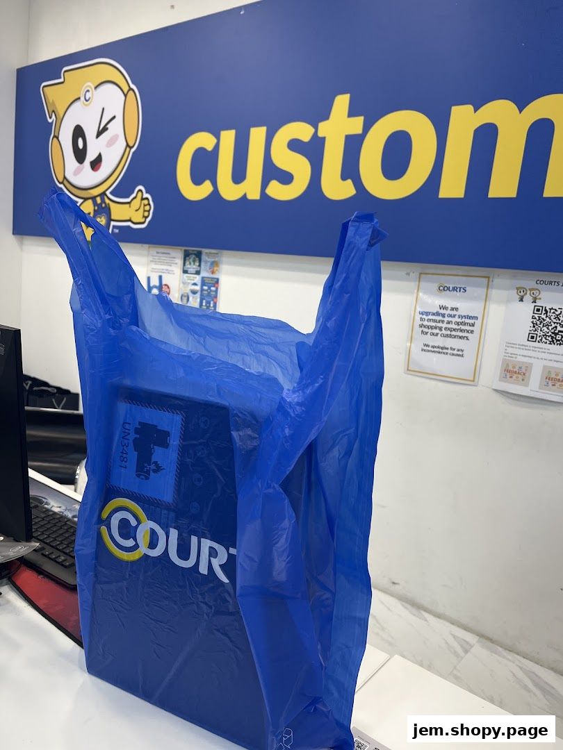 A blue COURTS shopping bag with a product inside, in front of a store sign.