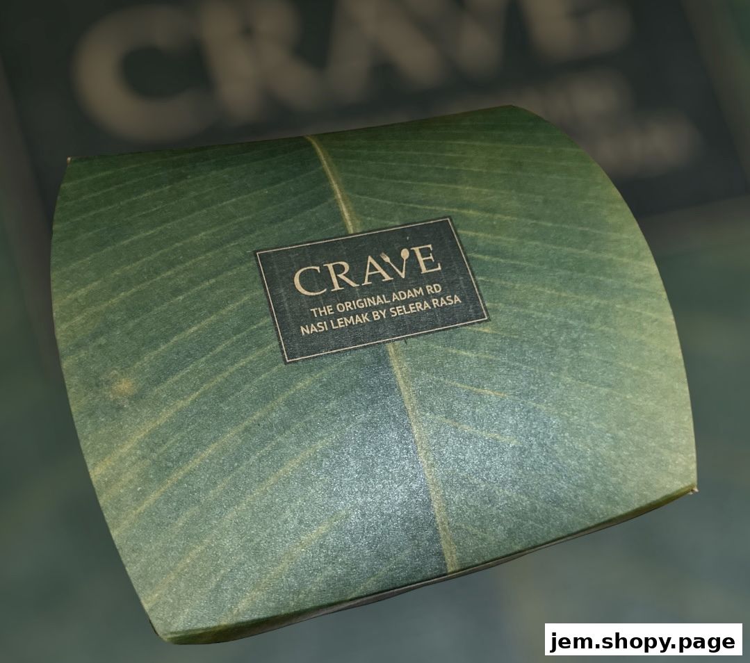 A close-up of a Crave Nasi Lemak food packaging with a leaf design.