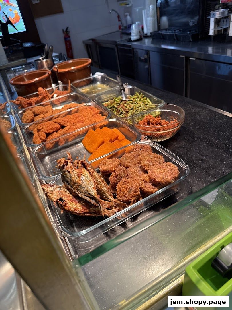 A display of various fried foods and side dishes in glass containers at a food stall.