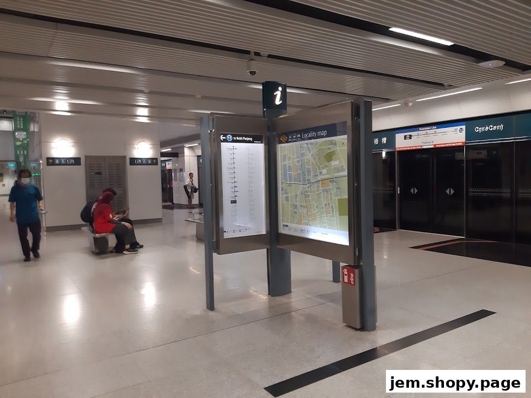 People waiting at a train station platform with maps and signage.