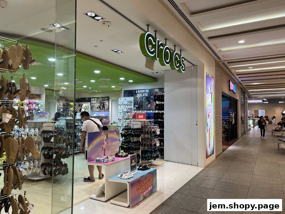 The entrance of a Crocs shoe store displaying various footwear and a customer browsing.