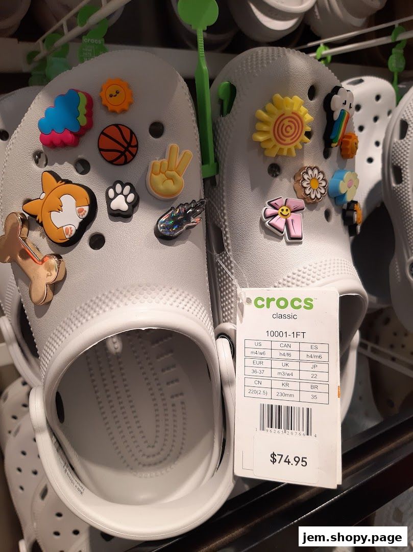 Close-up of white Crocs shoes adorned with colorful Jibbitz charms and a price tag.