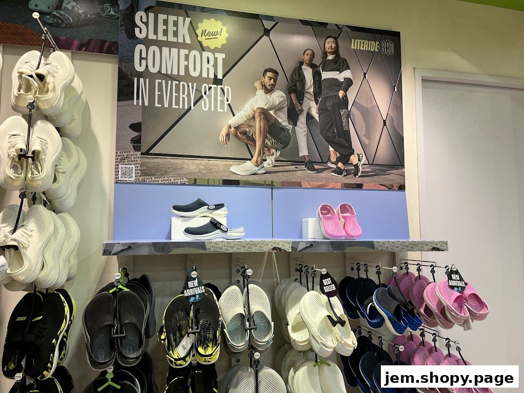 A display of Crocs shoes, featuring various styles and colors, with a large advertisement in the background.