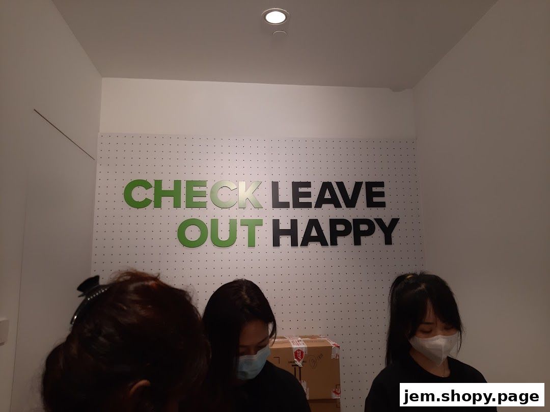 Three people stand in front of a wall with the text "CHECK LEAVE OUT HAPPY".