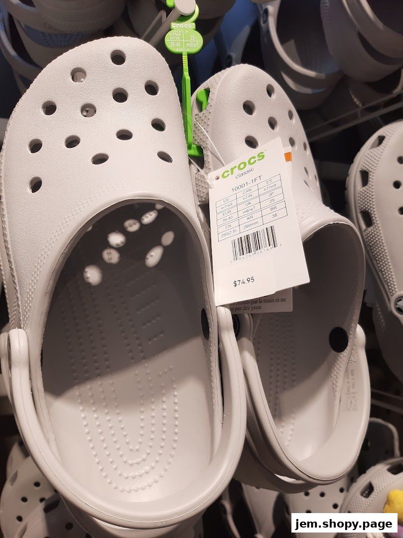 Close-up of light grey Crocs Classic clogs with a price tag showing $74.95.