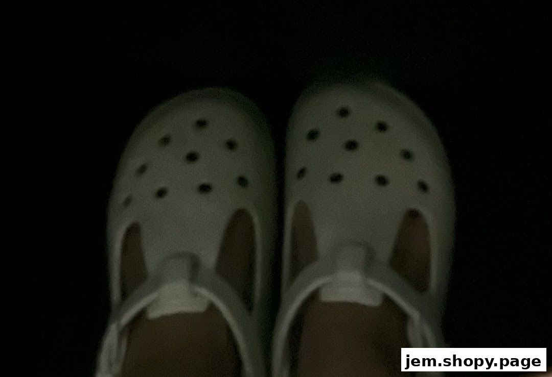 A pair of light-colored Crocs shoes with dark ventilation holes.
