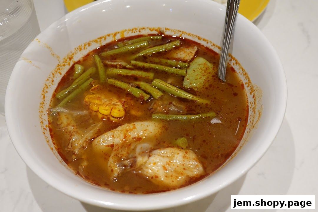 A close-up shot of a steaming bowl of flavorful soup with vegetables and meat.