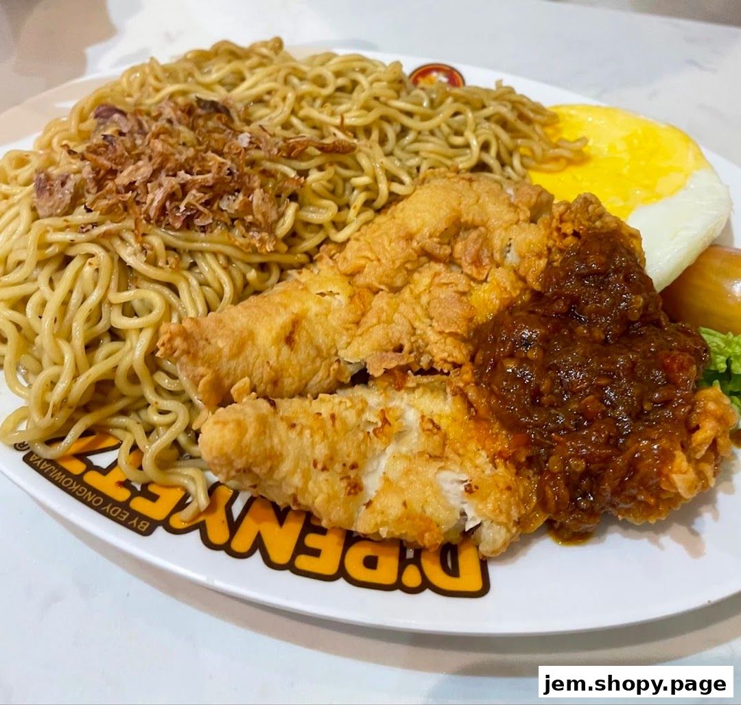 A plate of noodles with fried chicken, a fried egg, and chili sauce.