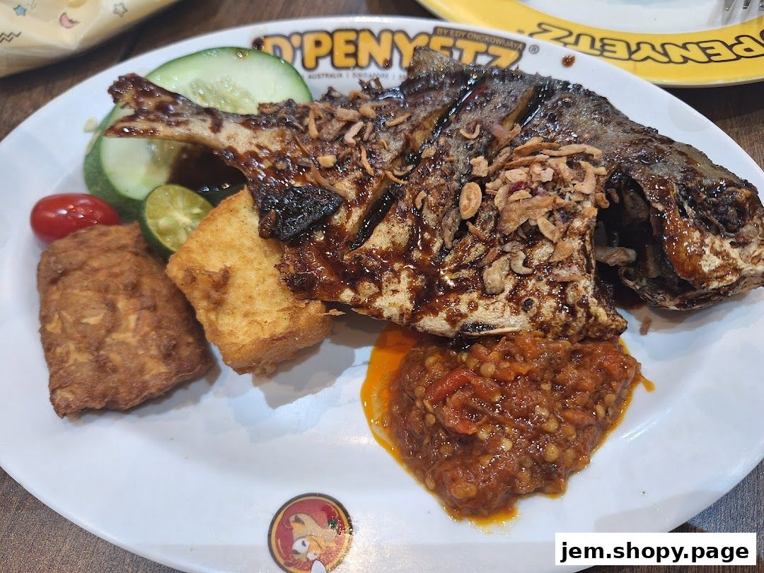 A plate of grilled fish with tofu, vegetables, and sambal sauce.