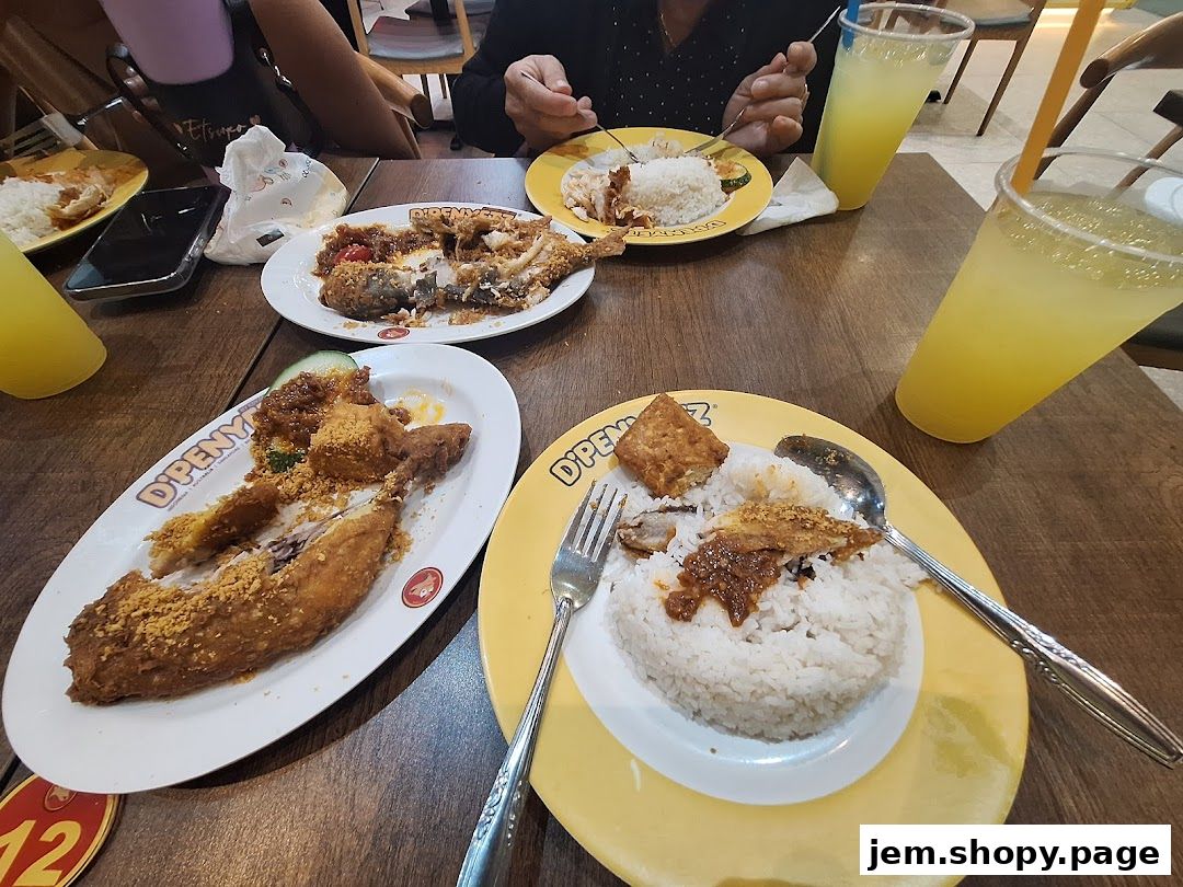 Plates of fried chicken and rice with drinks on a wooden table.