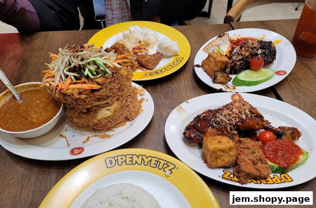 A table laden with delicious Indonesian dishes from D'Penyetz Jem, featuring fried items and rice.