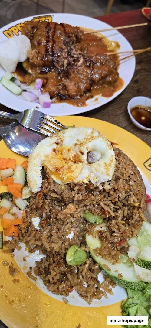 A plate of fried rice with a fried egg and a side of satay with peanut sauce.