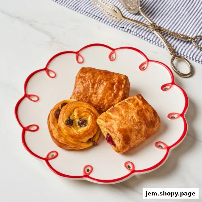 A plate of three delicious pastries, including a pain aux raisins and two chocolate or fruit-filled pastries.